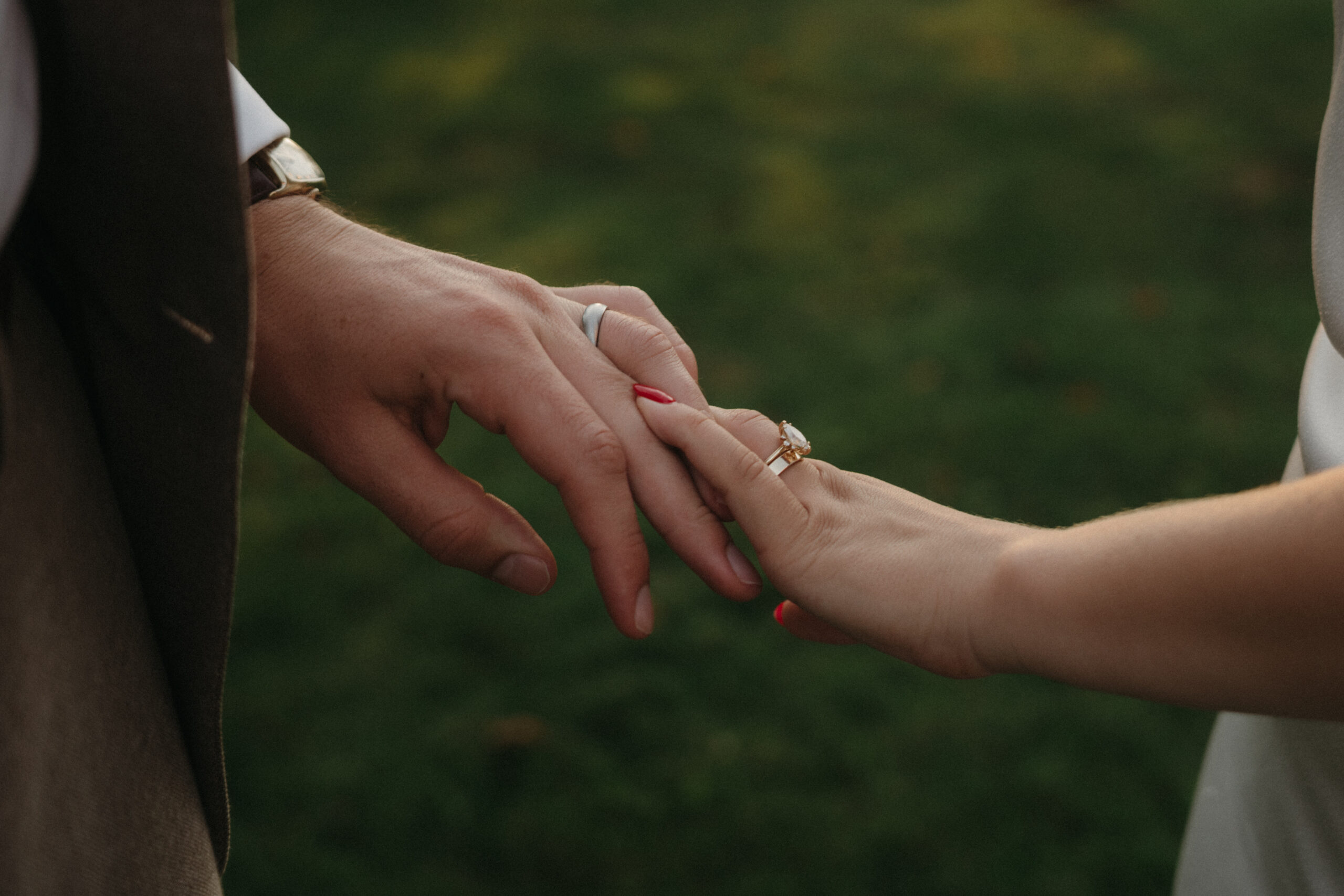 close up of newly weds holding hands, wedding bands on fingers